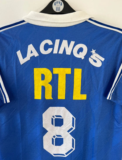 Maillot de foot vintage extérieur bleu du PSG saison 1988/1989. On peut retrouver l'équipementier Adidas et le sponsor RTL, La Cinq et Canal +. Il s'agit d'un maillot authentique d'époque.