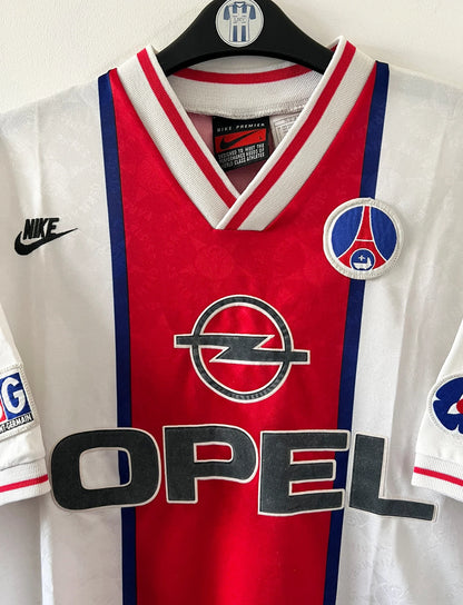 Maillot de foot vintage extérieur blanc du PSG 1995/1996. On peut retrouver la bande hechter avec l'équipementier Nike et le sponsor Opel. Il s'agit d'un maillot authentique d'époque.