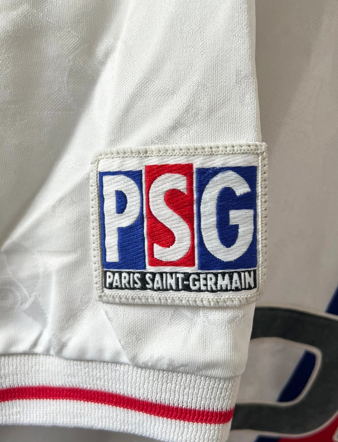 Maillot de foot vintage extérieur blanc du PSG 1995/1996. On peut retrouver la bande hechter avec l'équipementier Nike et le sponsor Opel. Il s'agit d'un maillot authentique d'époque.