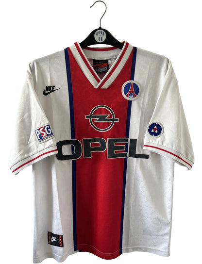 Maillot de foot vintage extérieur blanc du PSG 1995/1996. On peut retrouver la bande hechter avec l'équipementier Nike et le sponsor Opel. Il s'agit d'un maillot authentique d'époque.