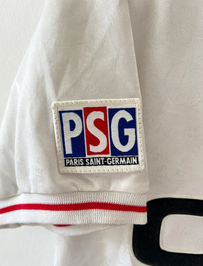 Maillot de foot vintage extérieur blanc et rouge du PSG 1995/1996. On peut retrouver l'équipementier Nike et le sponsor Opel. Le maillot est floqué du numéro 7 Leonardo. Il s'agit d'un maillot authentique d'époque. 