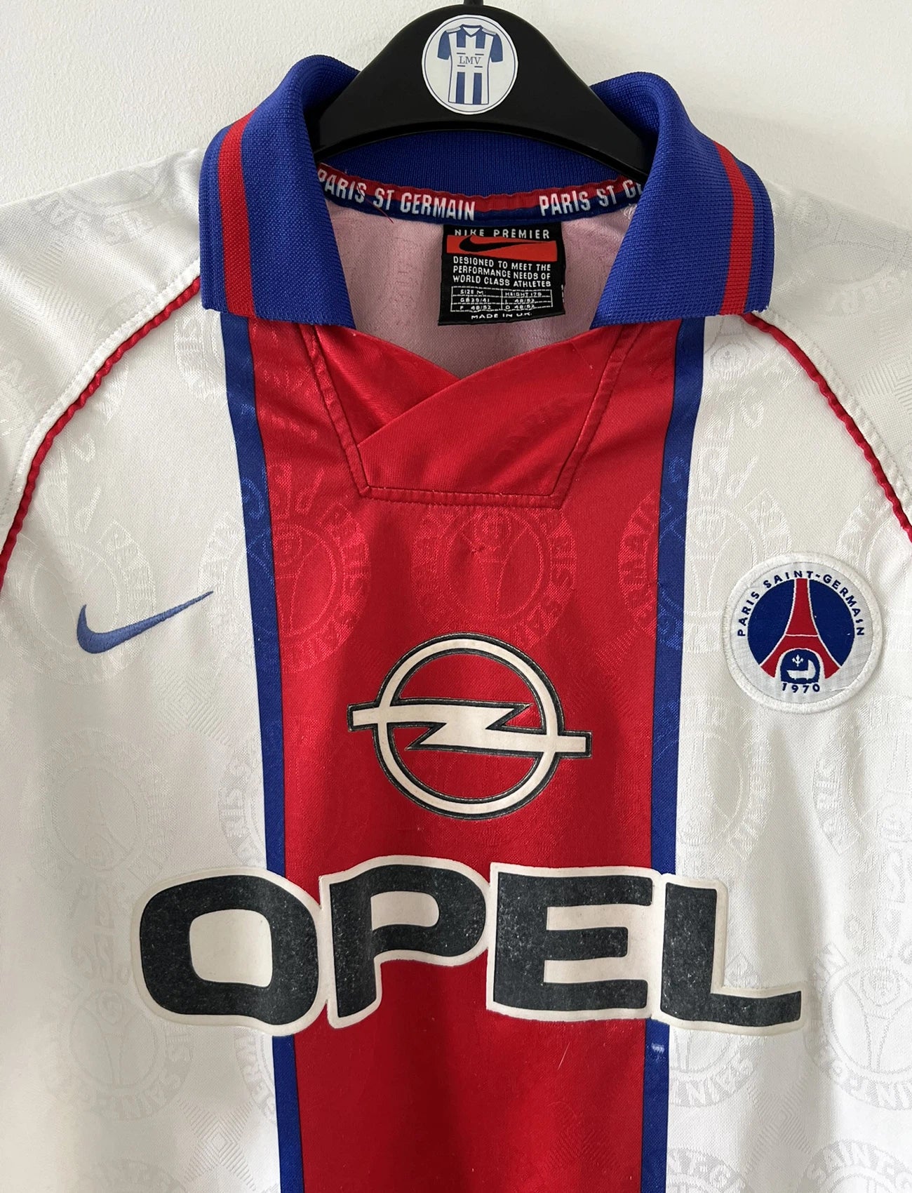 Maillot de foot vintage blanc rouge et bleu du PSG de la saison 1996/1997. On peut retrouver l'équipementier nike et le sponsor opel. Il s'agit d'un maillot authentique d'époque.