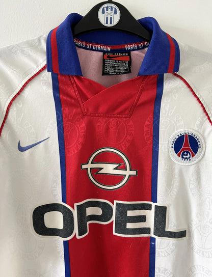Maillot de foot vintage blanc rouge et bleu du PSG de la saison 1996/1997. On peut retrouver l'équipementier nike et le sponsor opel. Il s'agit d'un maillot authentique d'époque.