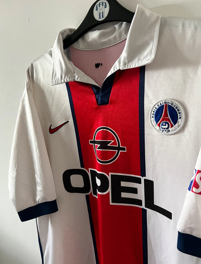 Maillot extérieur PSG blanc et rouge de la saison 1998/1999. On peut retrouver l'équipementier Nike et le sponsor Opel. Il s'agit d'un maillot authentique d'époque.