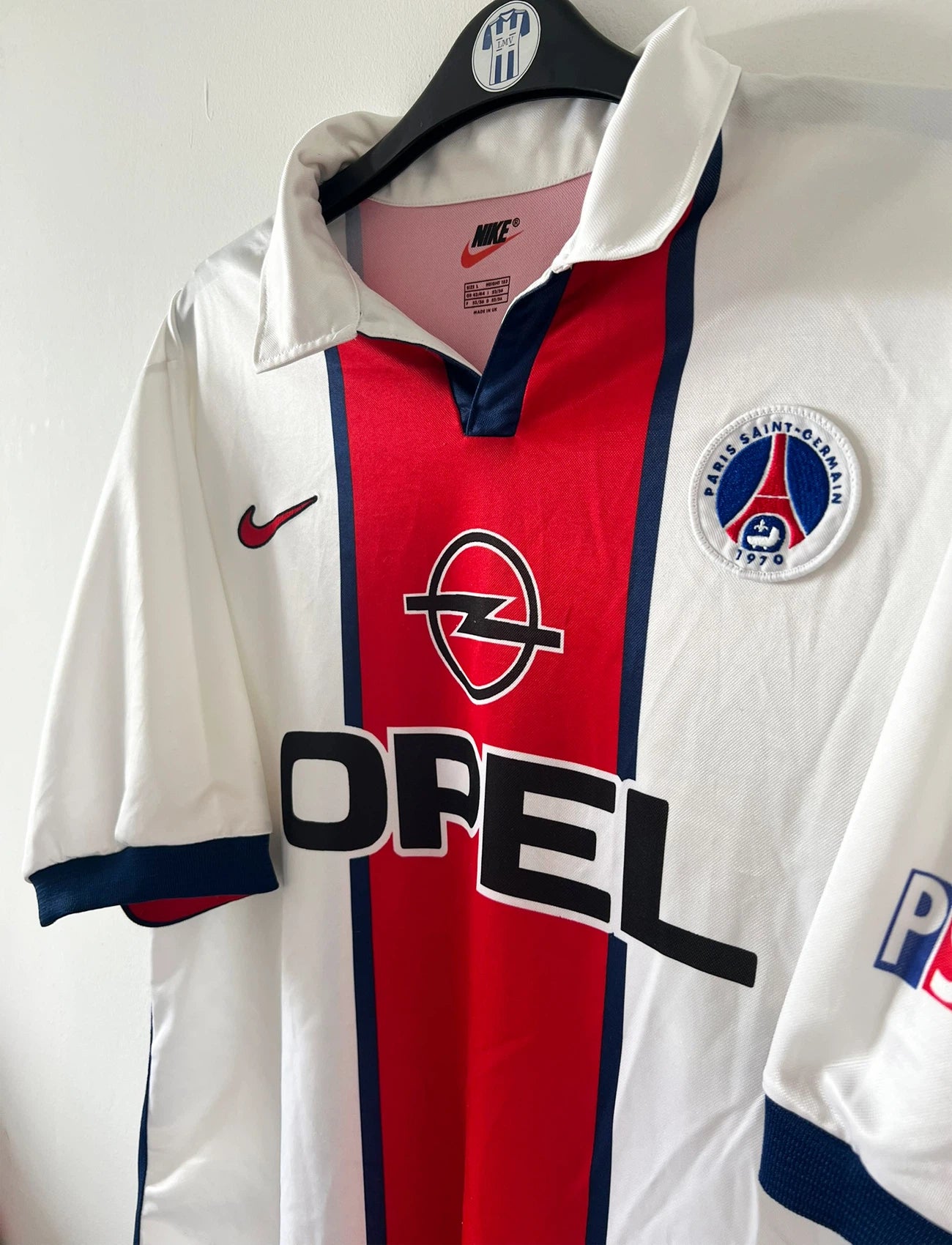 Maillot extérieur PSG blanc et rouge de la saison 1998/1999. On peut retrouver l'équipementier Nike et le sponsor Opel. Il s'agit d'un maillot authentique d'époque.