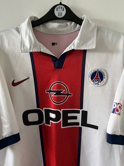 Maillot extérieur PSG blanc et rouge de la saison 1998/1999. On peut retrouver l'équipementier Nike et le sponsor Opel. Il s'agit d'un maillot authentique d'époque.