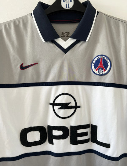 Maillot de foot vintage extérieur gris du PSG de la saison 2000/2001. On peut retrouver l'équipementier Nike et le sponsor Opel. Il s'agit d'un maillot authentique d'époque.