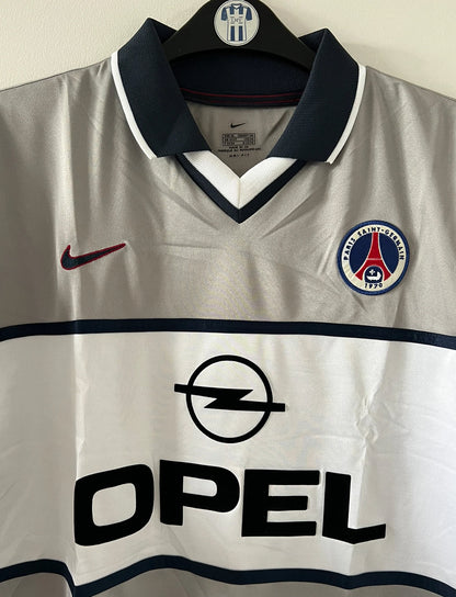 Maillot de foot vintage extérieur gris du PSG de la saison 2000/2001. On peut retrouver l'équipementier Nike et le sponsor Opel. Il s'agit d'un maillot authentique d'époque.