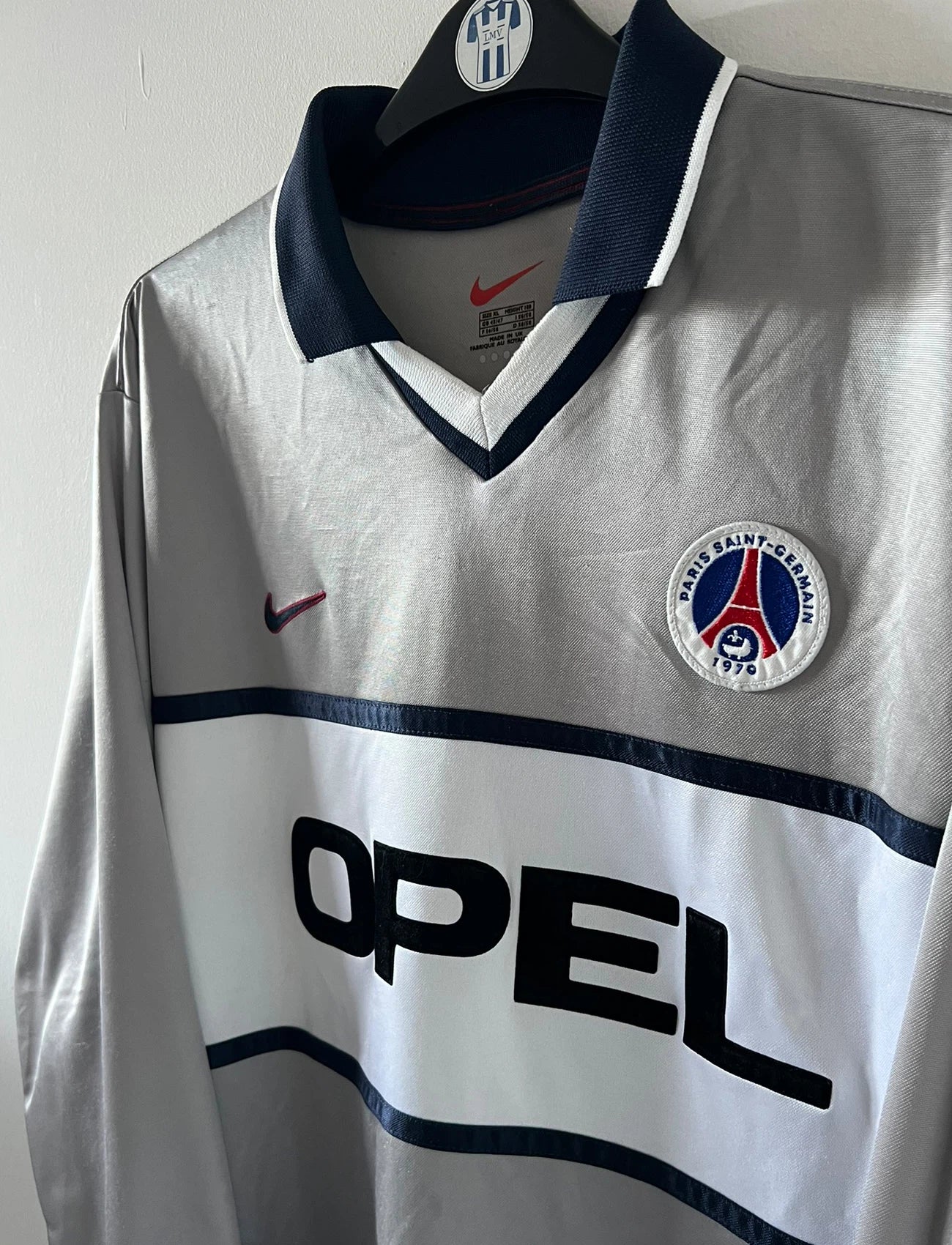 Maillot de foot vintage domicile gris du PSG de la saison 2000/2001. On peut retrouver l'équipementier Nike et le sponsor Opel. Il s'agit d'un maillot authentique d'époque, issu du stock pro du PSG.