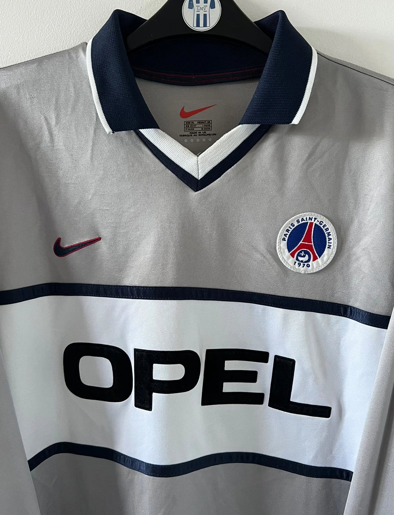 Maillot de foot vintage domicile gris du PSG de la saison 2000/2001. On peut retrouver l'équipementier Nike et le sponsor Opel. Il s'agit d'un maillot authentique d'époque, issu du stock pro du PSG.