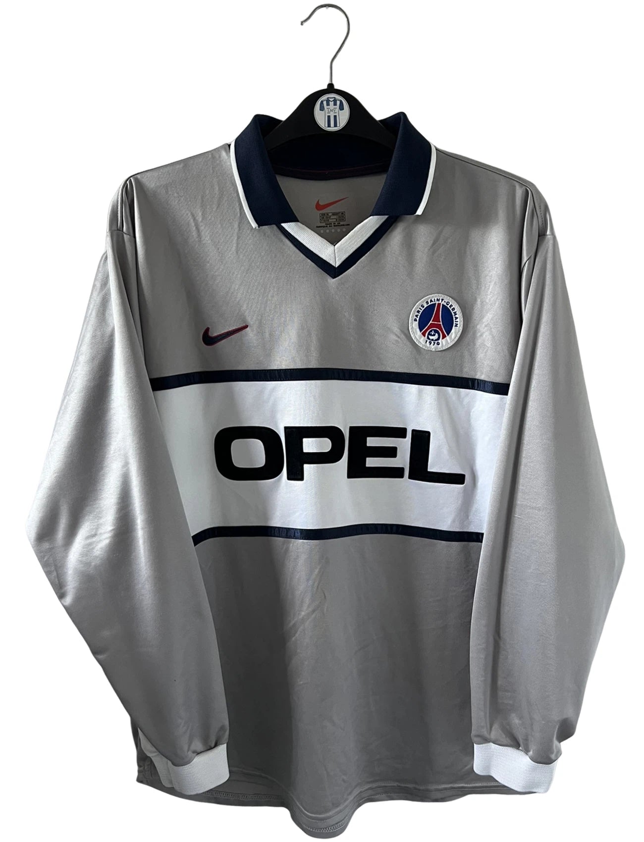 Maillot de foot vintage domicile gris du PSG de la saison 2000/2001. On peut retrouver l'équipementier Nike et le sponsor Opel. Il s'agit d'un maillot authentique d'époque, issu du stock pro du PSG.