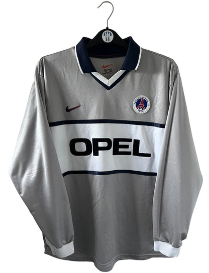 Maillot de foot vintage domicile gris du PSG de la saison 2000/2001. On peut retrouver l'équipementier Nike et le sponsor Opel. Il s'agit d'un maillot authentique d'époque, issu du stock pro du PSG.