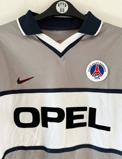 Maillot de foot vintage extérieur gris du PSG de la saison 2000/2001. On peut retrouver l'équipementier Nike et le sponsor Opel. Il s'agit d'un maillot authentique d'époque issu du stock pro du club.