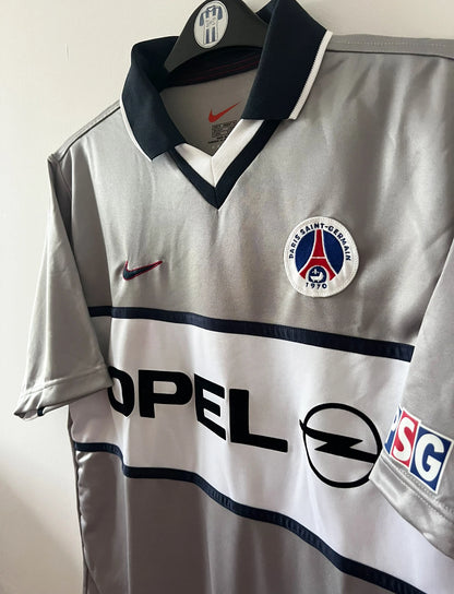 Maillot de foot vintage extérieur gris du PSG de la saison 2000/2001. On peut retrouver l'équipementier Nike et le sponsor Opel. Il s'agit d'un maillot authentique d'époque.