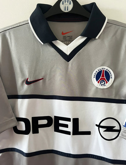 Maillot de foot vintage extérieur gris du PSG de la saison 2000/2001. On peut retrouver l'équipementier Nike et le sponsor Opel. Il s'agit d'un maillot authentique d'époque.