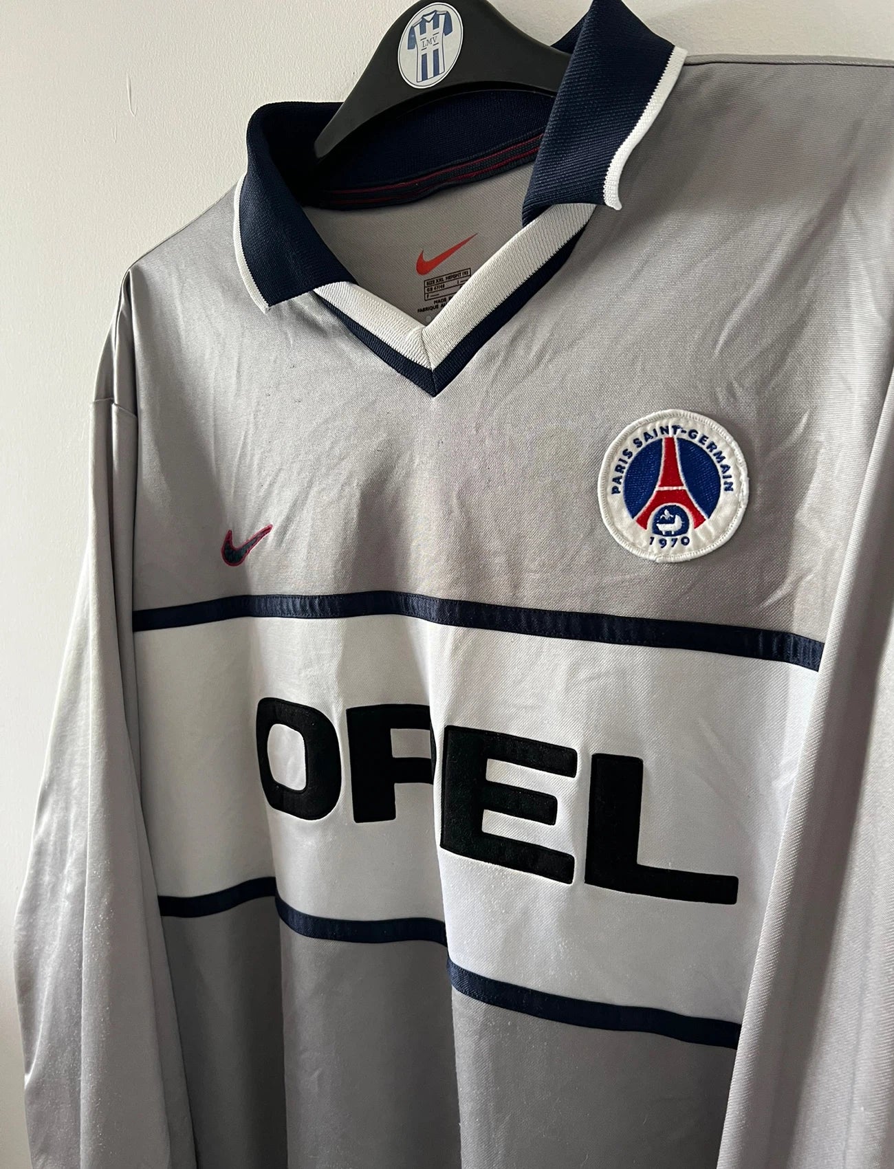 Maillot de foot vintage extérieur gris et blanc du PSG saison 2000/2001. On peut retrouver l'équipementier Nike et le sponsor Opel. Il s'agit d'un maillot authentique d'époque issu du stock pro.