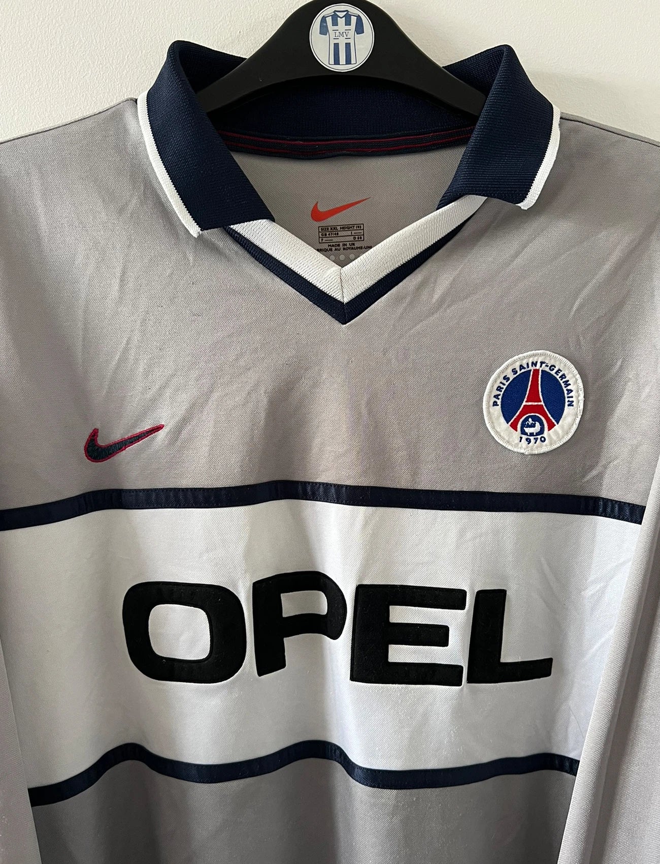 Maillot de foot vintage extérieur gris et blanc du PSG saison 2000/2001. On peut retrouver l'équipementier Nike et le sponsor Opel. Il s'agit d'un maillot authentique d'époque issu du stock pro.