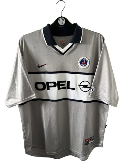 Maillot de foot vintage extérieur gris du PSG 2001/2002. On peut retrouver l'équipementier Nike et le sponsor Opel. Il s'agit d'un maillot authentique d'époque.