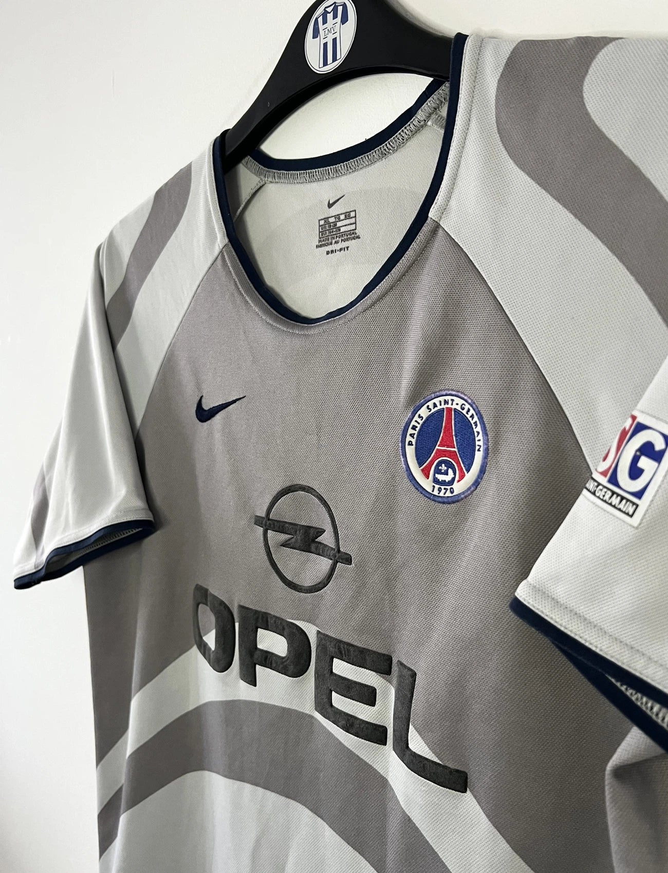 Maillot de foot vintage extérieur gris du PSG de la saison 2001/2002. On peut retrouver l'équipementier Nike et le sponsor Opel. Il s'agit d'un maillot authentique d'époque