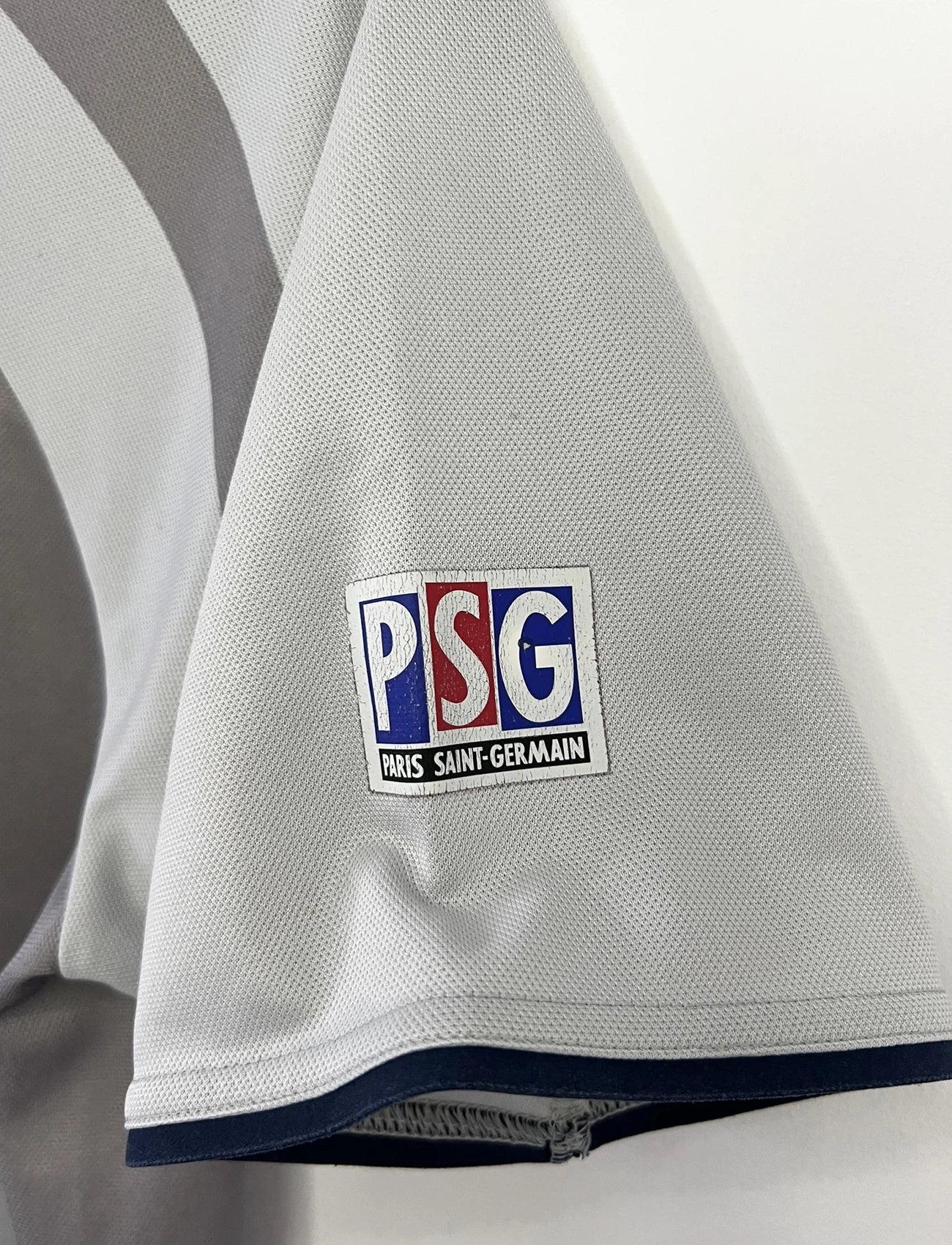 Maillot de foot vintage extérieur gris du PSG de la saison 2001/2002. On peut retrouver l'équipementier Nike et le sponsor Opel. Il s'agit d'un maillot authentique d'époque