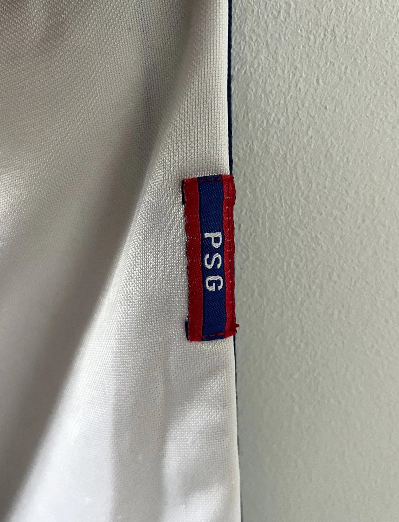 Maillot extérieur PSG blanc et rouge de la saison 1998/1999. On peut retrouver l'équipementier Nike et le sponsor Opel. Il s'agit d'un maillot authentique d'époque.