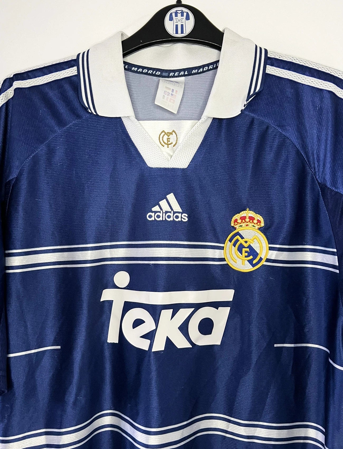 Maillot de foot vintage extérieur bleu du Real Madrid de la saison 1998/1999. On peut retrouver l'équipementier Adidas et le sponsor Teka. Il s'agit d'un maillot authentique d'époque.