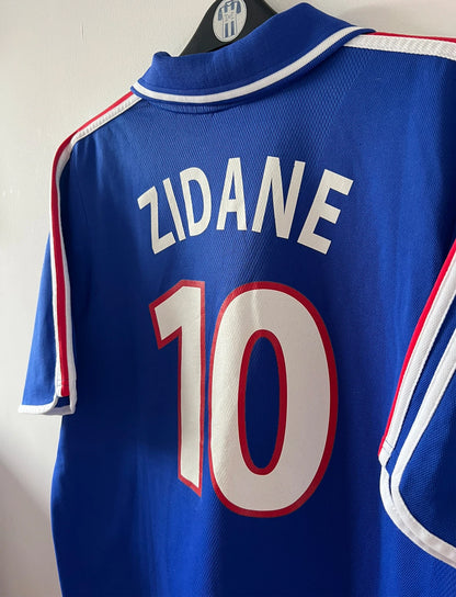 Maillot de foot vintage domicile bleu de l'Equipe de France 2000. On peut retrouver l'équipementier Adidas. Le maillot est floqué du numéro 10 Zinedine Zidane. Il s'agit d'un maillot authentique d'époque comportant la mention France-Italie 02-07-2000.