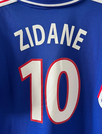 Maillot de foot vintage domicile bleu de l'Equipe de France 2000. On peut retrouver l'équipementier Adidas. Le maillot est floqué du numéro 10 Zinedine Zidane. Il s'agit d'un maillot authentique d'époque comportant la mention France-Italie 02-07-2000.