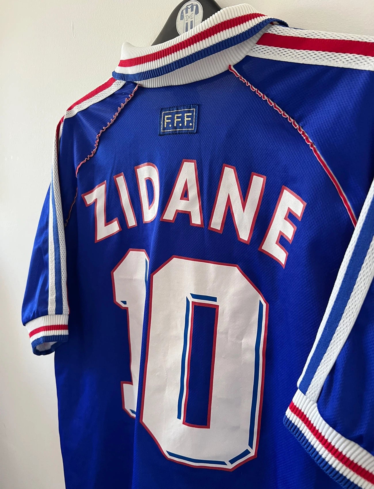 Maillot foot vintage domicile equipe de france 1998 bleu blanc et rouge. On peut retrouver l'équipementier adidas. Il s'agit d'un maillot authentique d'époque. Le maillot est floqué du numéro 10 Zinedine Zidane et comporte également sa signature avec la mention "pour toi Zinedine Zidane"