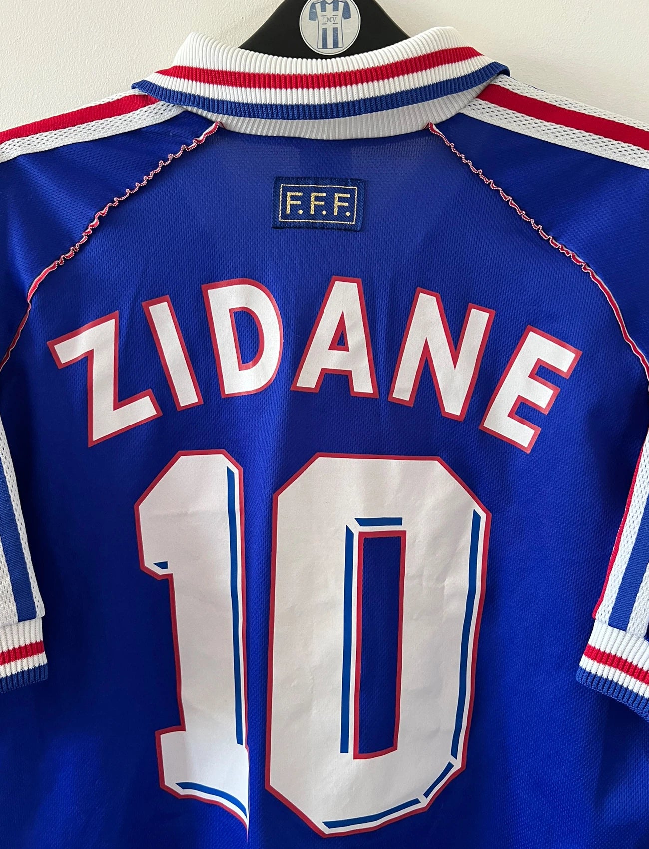 Maillot foot vintage domicile equipe de france 1998 bleu blanc et rouge. On peut retrouver l'équipementier adidas. Il s'agit d'un maillot authentique d'époque. Le maillot est floqué du numéro 10 Zinedine Zidane et comporte également sa signature avec la mention "pour toi Zinedine Zidane"