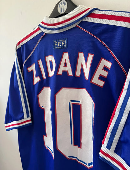Maillot foot vintage domicile equipe de france 1998 bleu blanc et rouge. On peut retrouver l'équipementier adidas. Il s'agit d'un maillot authentique d'époque. Le maillot est floqué du numéro 10 Zinedine Zidane
