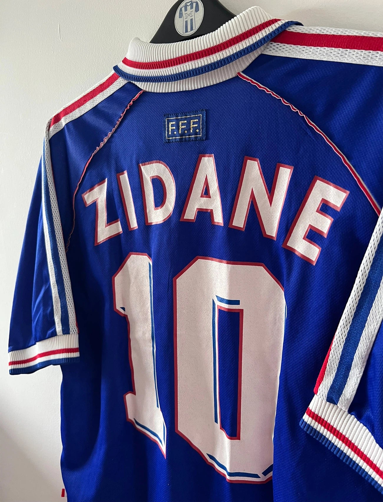 Maillot foot vintage domicile equipe de france 1998 bleu blanc et rouge. On peut retrouver l'équipementier adidas. Il s'agit d'un maillot authentique d'époque. Le maillot est floqué du numéro 10 Zinedine Zidane et comporte également sa signature avec la mention "pour toi Zinedine Zidane"