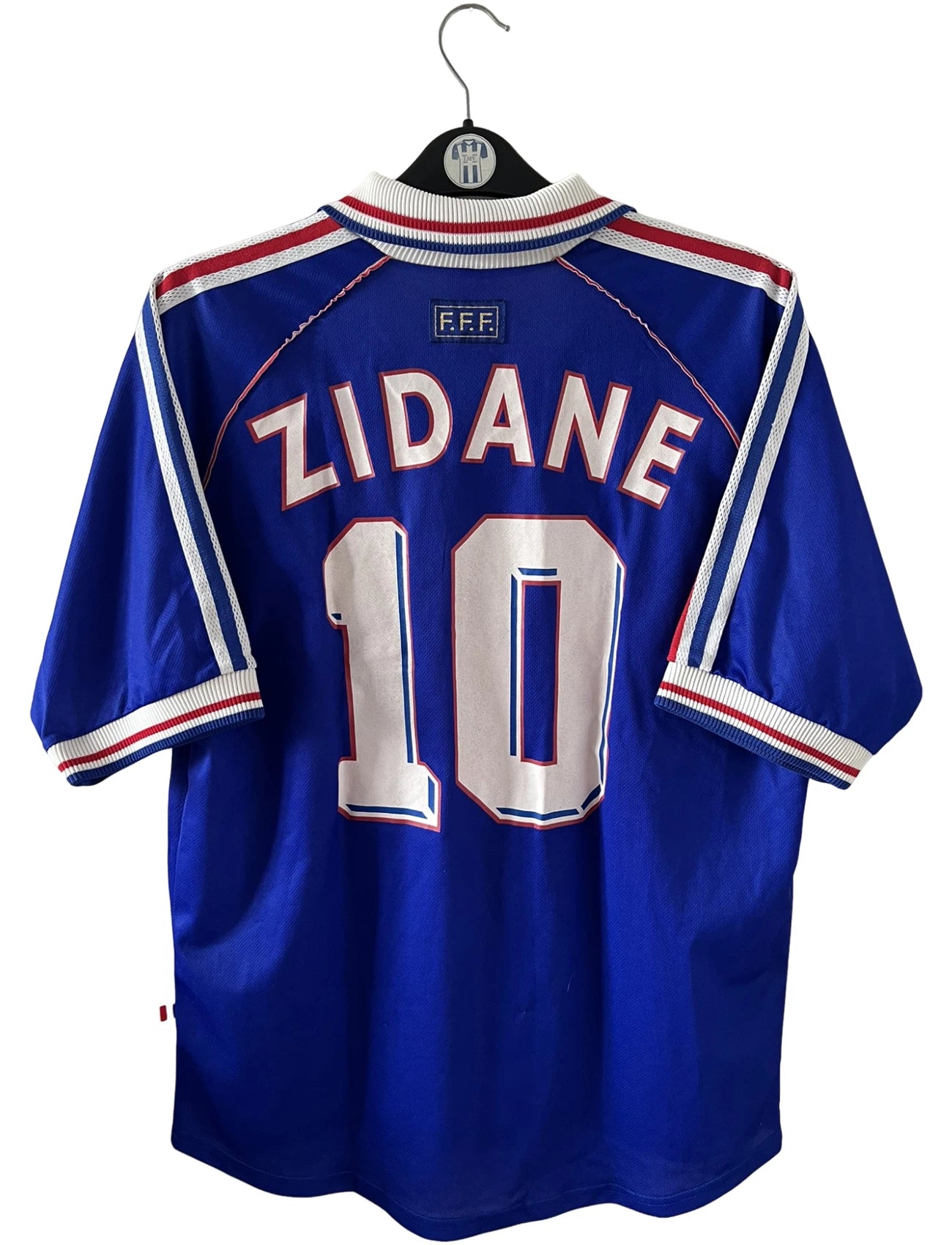 Maillot foot vintage domicile equipe de france 1998 bleu blanc et rouge. On peut retrouver l'équipementier adidas. Il s'agit d'un maillot authentique d'époque. Le maillot est floqué du numéro 10 Zinedine Zidane et comporte également sa signature avec la mention "pour toi Zinedine Zidane"