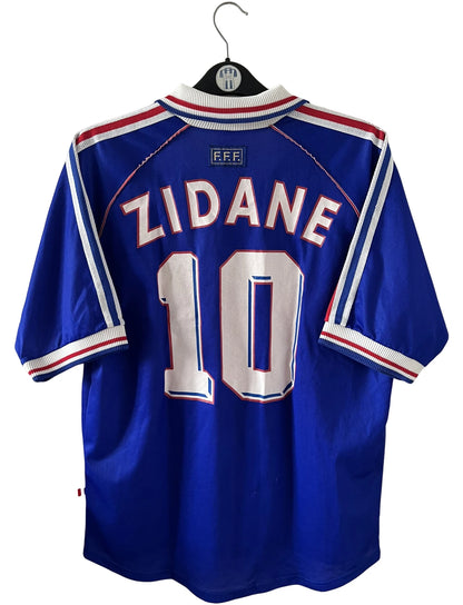 Maillot foot vintage domicile equipe de france 1998 bleu blanc et rouge. On peut retrouver l'équipementier adidas. Il s'agit d'un maillot authentique d'époque. Le maillot est floqué du numéro 10 Zinedine Zidane et comporte également sa signature avec la mention "pour toi Zinedine Zidane"