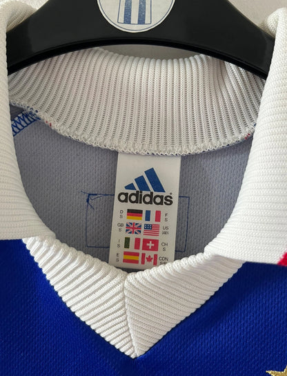Maillot foot vintage domicile equipe de france 1998 bleu blanc et rouge. On peut retrouver l'équipementier adidas. Il s'agit d'un maillot authentique d'époque. Le maillot est floqué du numéro 10 Zinedine Zidane et comporte également sa signature avec la mention "pour toi Zinedine Zidane"
