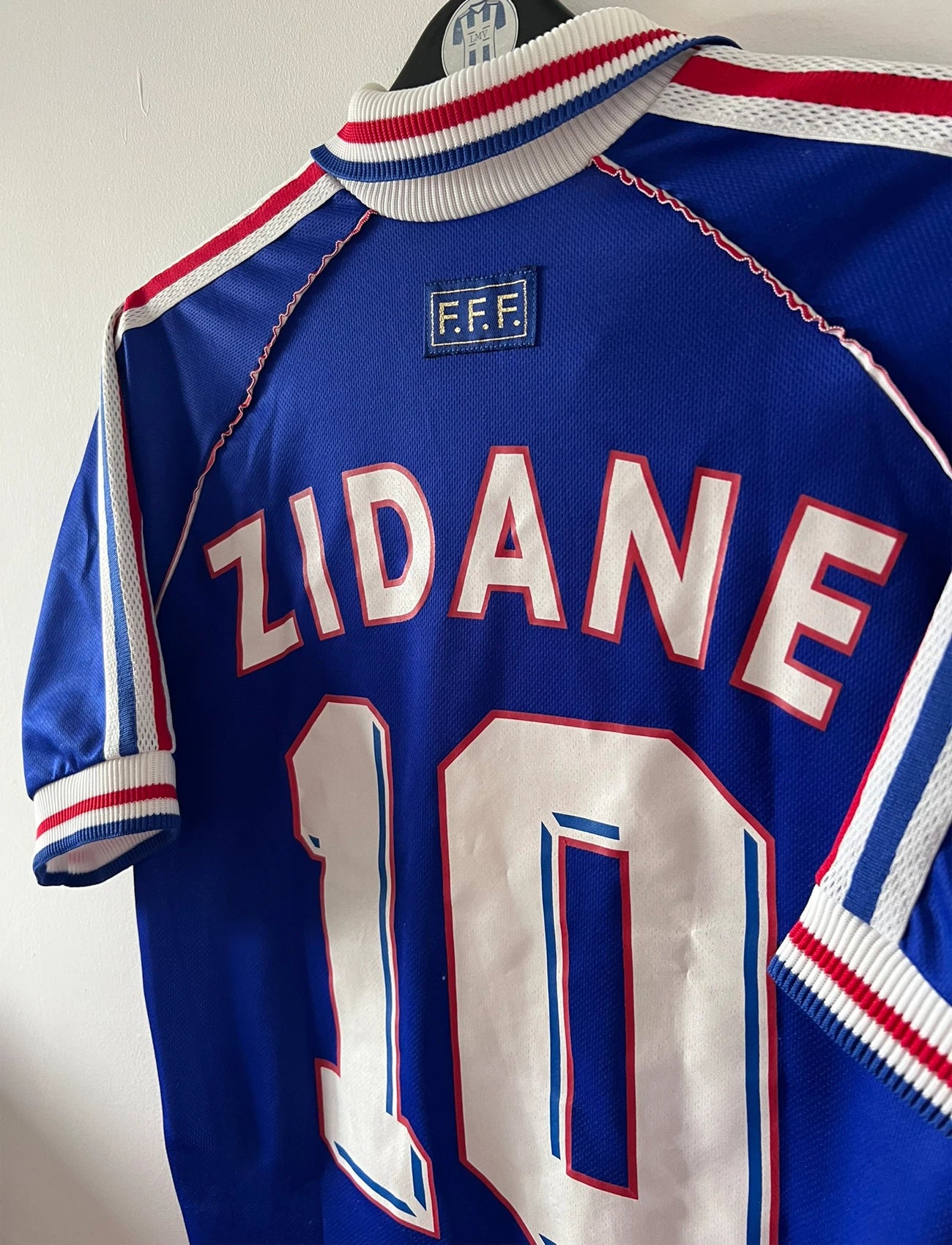 Maillot foot vintage domicile equipe de france 1998 bleu blanc et rouge. On peut retrouver l'équipementier adidas. Il s'agit d'un maillot authentique d'époque. Le maillot est floqué du numéro 10 Zinedine Zidane et comporte également sa signature avec la mention "pour toi Zinedine Zidane"