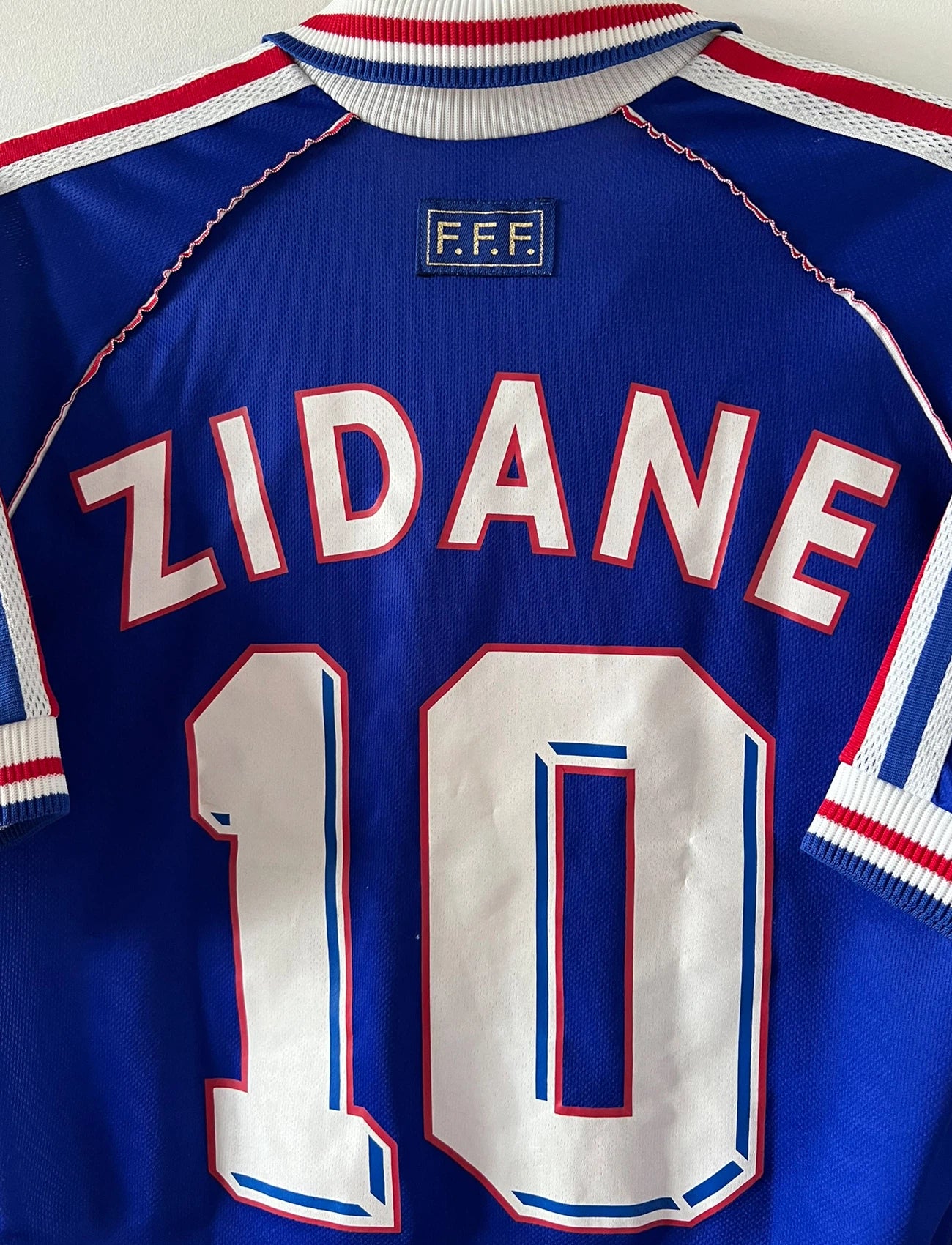 Maillot foot vintage domicile equipe de france 1998 bleu blanc et rouge. On peut retrouver l'équipementier adidas. Il s'agit d'un maillot authentique d'époque. Le maillot est floqué du numéro 10 Zinedine Zidane et comporte également sa signature avec la mention "pour toi Zinedine Zidane"