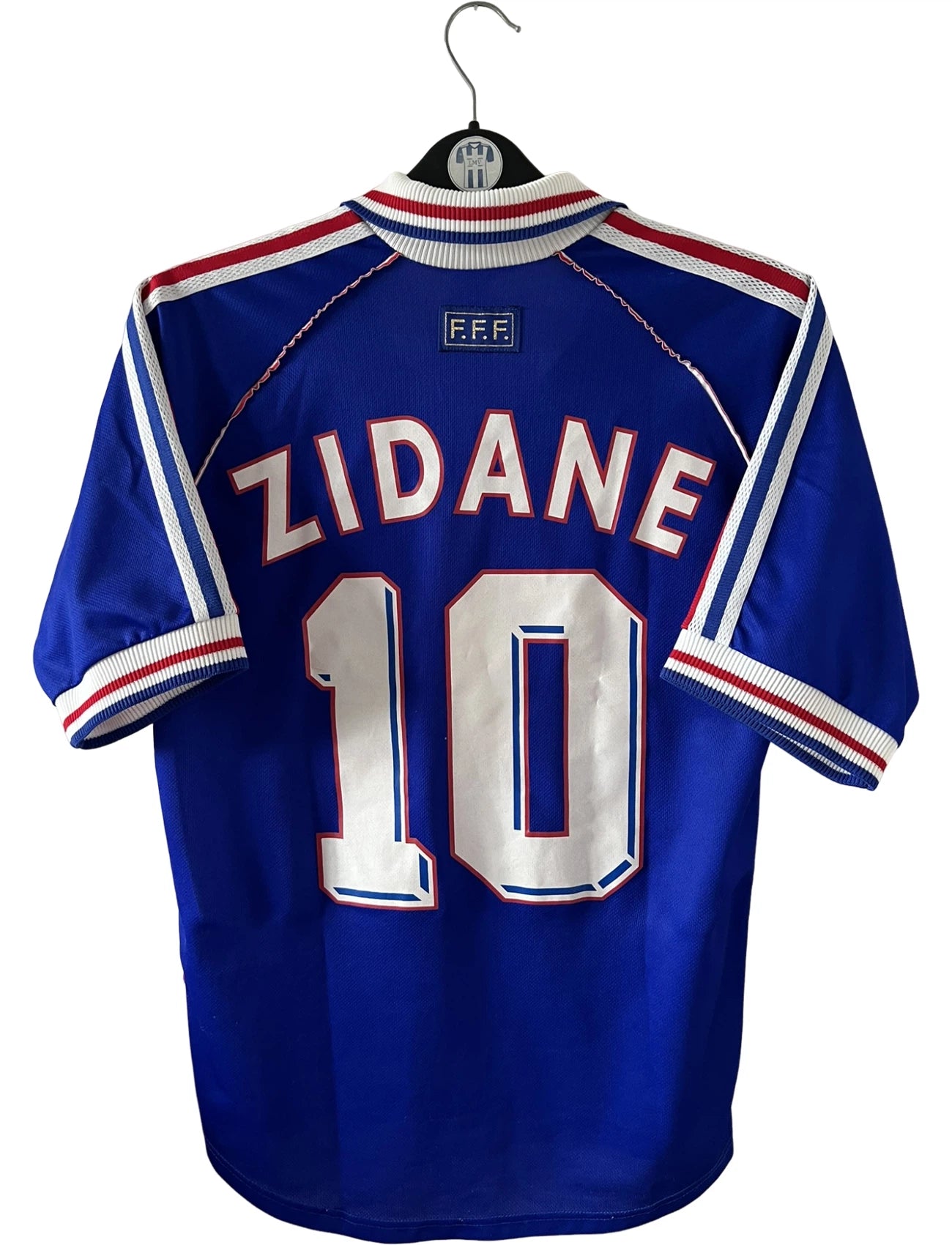 Maillot foot vintage domicile equipe de france 1998 bleu blanc et rouge. On peut retrouver l'équipementier adidas. Il s'agit d'un maillot authentique d'époque. Le maillot est floqué du numéro 10 Zinedine Zidane et comporte également sa signature avec la mention "pour toi Zinedine Zidane"