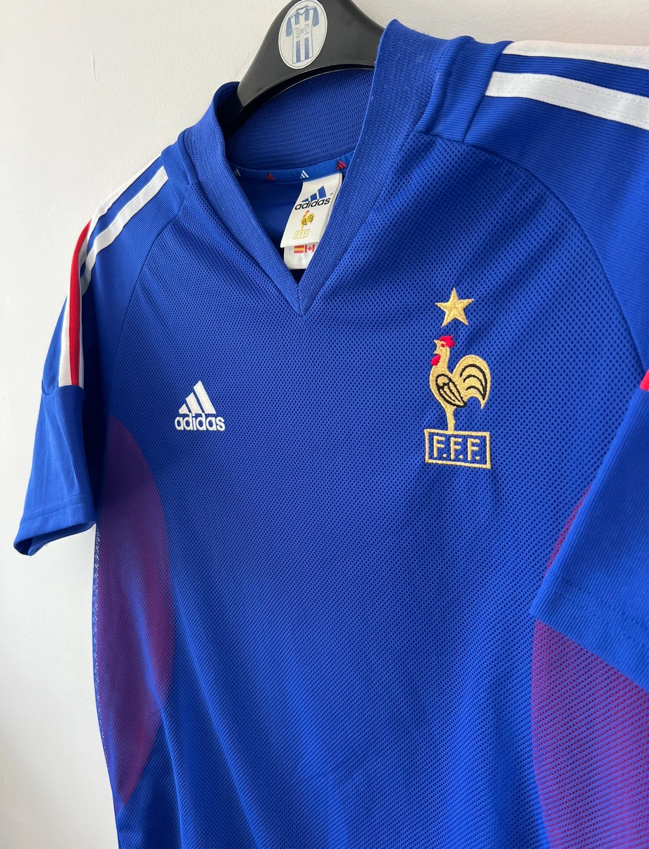 Maillot de foot vintage domicile bleu de l'équipe de france 2002. On peut retrouver l'équipementier Adidas et le flocage de Zidane. Il s'agit d'un maillot authentique d'époque.