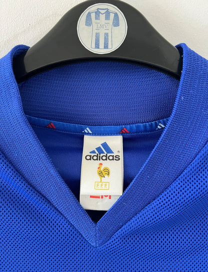 Maillot de foot vintage domicile bleu de l'équipe de france 2002. On peut retrouver l'équipementier Adidas et le flocage de Zidane. Il s'agit d'un maillot authentique d'époque.