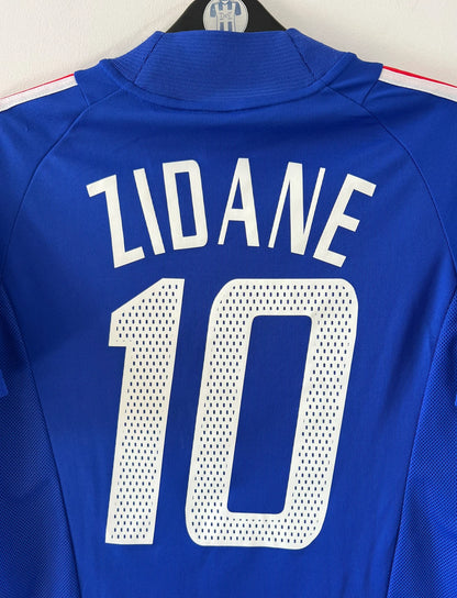 Maillot de foot vintage domicile bleu de l'équipe de france 2002. On peut retrouver l'équipementier Adidas et le flocage de Zidane. Il s'agit d'un maillot authentique d'époque.