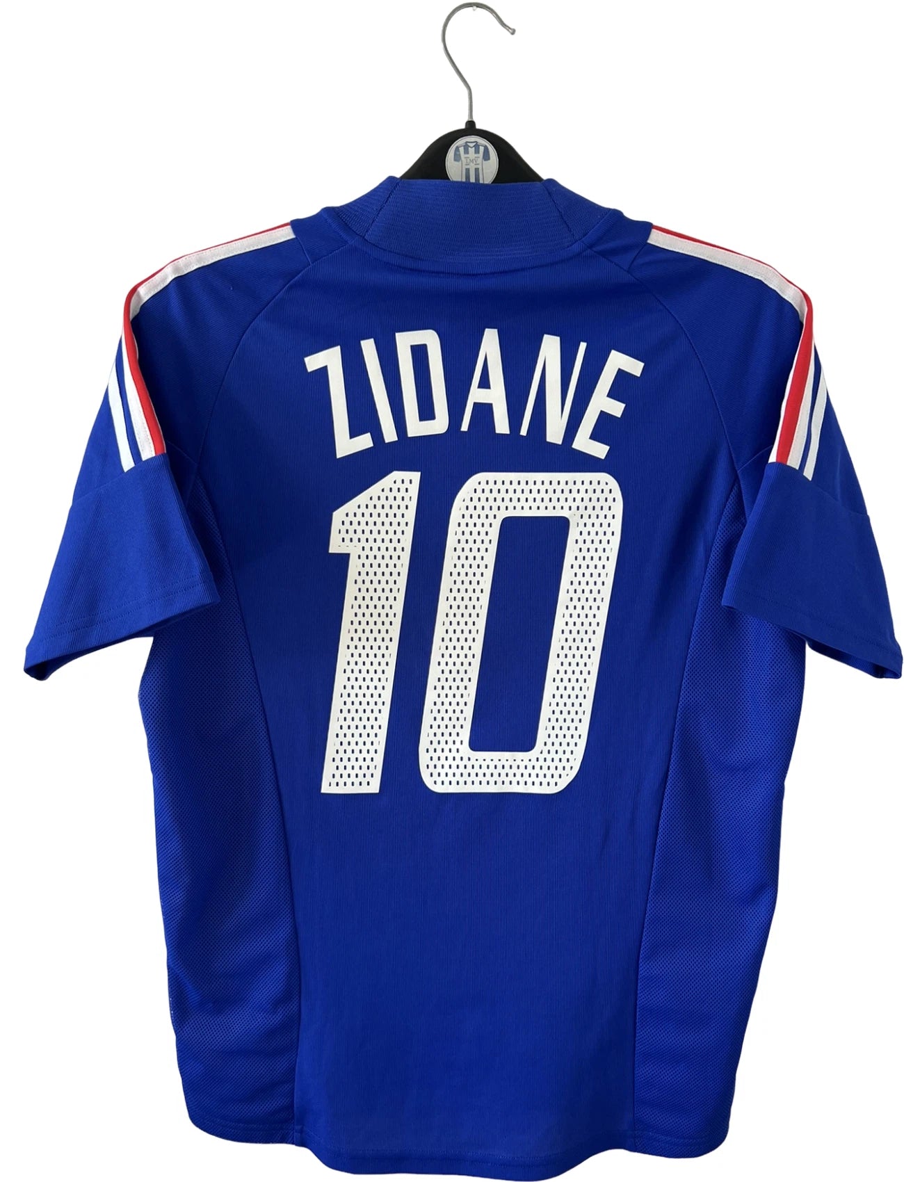 Maillot de foot vintage domicile bleu de l'équipe de france 2002. On peut retrouver l'équipementier Adidas et le flocage de Zidane. Il s'agit d'un maillot authentique d'époque.