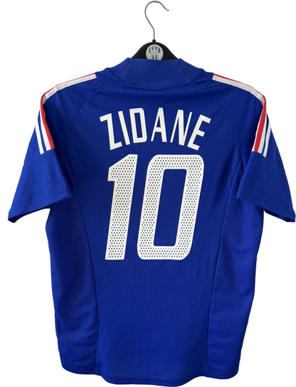 Maillot de foot vintage domicile bleu de l'équipe de france 2002. On peut retrouver l'équipementier Adidas et le flocage de Zidane. Il s'agit d'un maillot authentique d'époque.