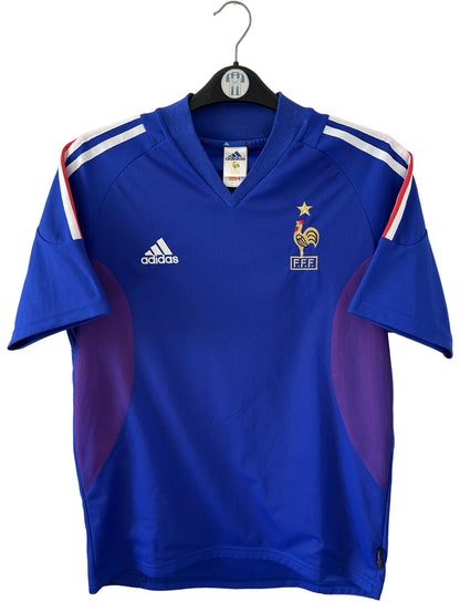 Maillot de foot vintage domicile bleu de l'équipe de france 2002. On peut retrouver l'équipementier Adidas et le flocage de Zidane. Il s'agit d'un maillot authentique d'époque.
