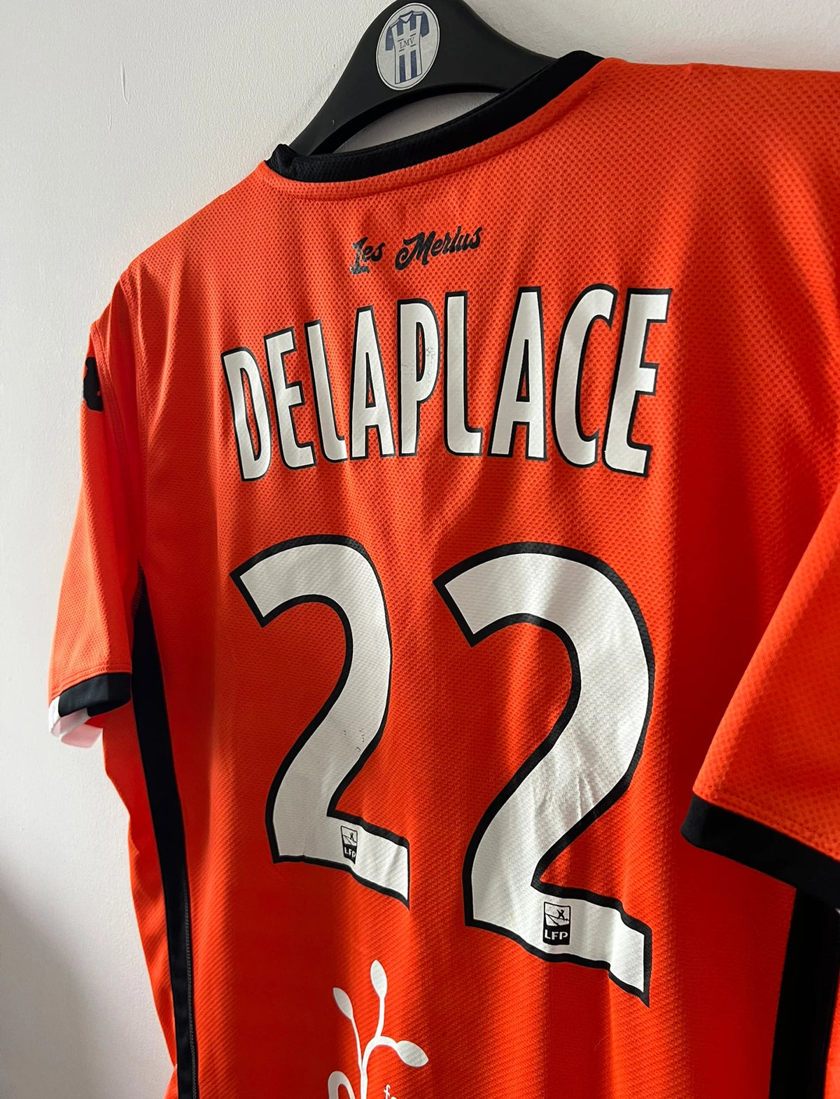 Maillot de foot vintage domicile orange du FC Lorient de la saison 2018/2019. On peut retrouver l'équipementier Kappa et les sponsors Jean Floc'h, B&B et Breizh Cola. Le maillot est floqué du numéro 22 Jonathan Delaplace. Il s'agit d'un maillot authentique d'époque.