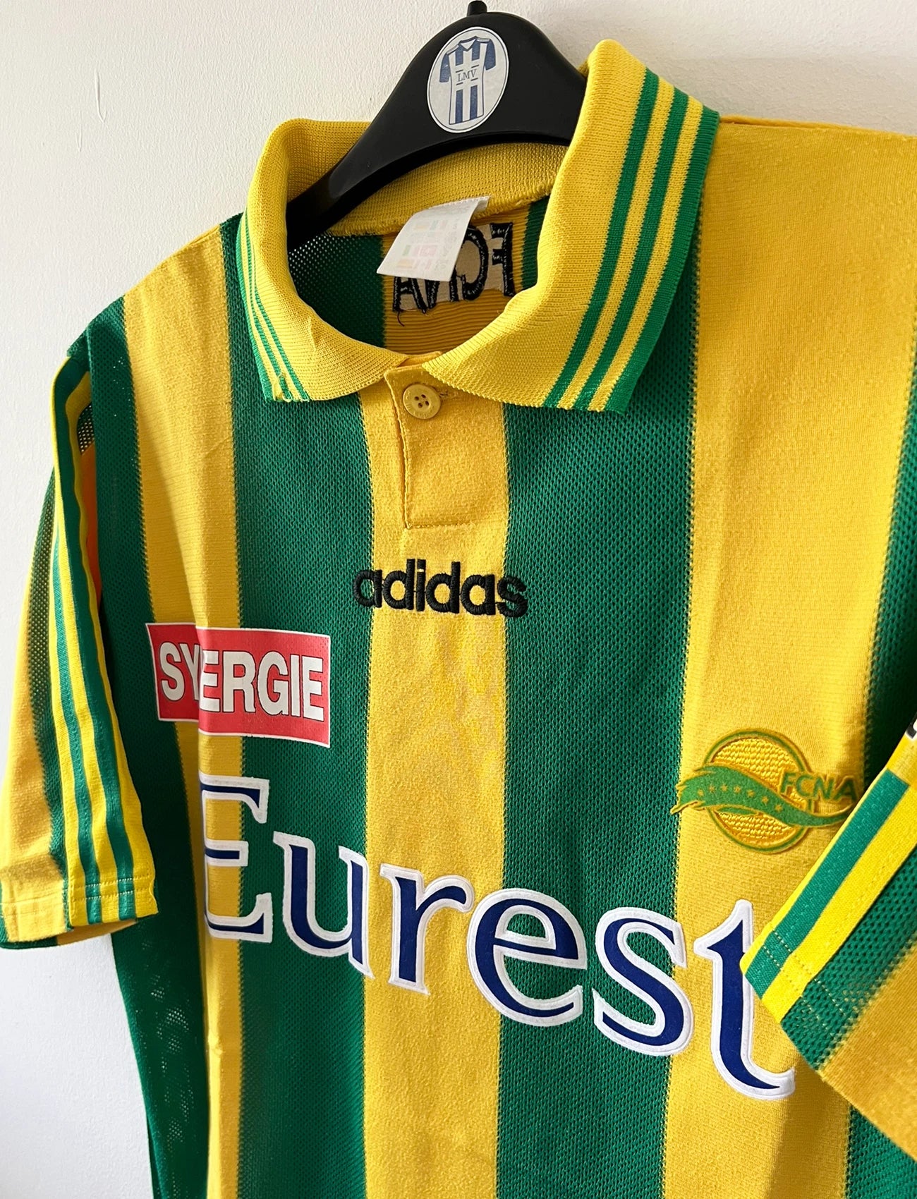 Maillot de foot vintage domicile jaune et vert du FC Nantes 1996/1997. On peut retrouver l'équipementier Adidas et le sponsor Eurest et Playstation. Il s'agit d'un maillot authentique d'époque.
