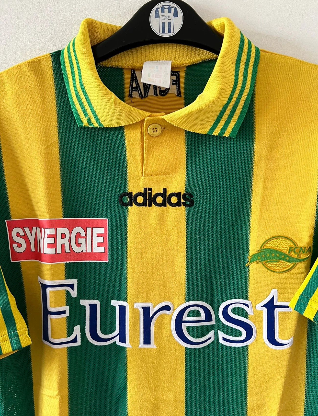 Maillot de foot vintage domicile jaune et vert du FC Nantes 1996/1997. On peut retrouver l'équipementier Adidas et le sponsor Eurest et Playstation. Il s'agit d'un maillot authentique d'époque.
