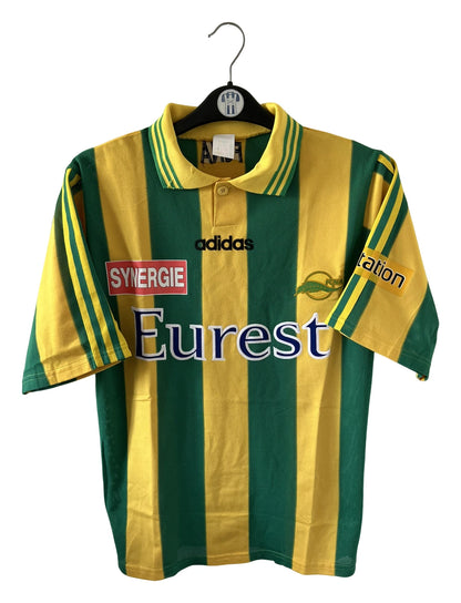 Maillot de foot vintage domicile jaune et vert du FC Nantes 1996/1997. On peut retrouver l'équipementier Adidas et le sponsor Eurest et Playstation. Il s'agit d'un maillot authentique d'époque.