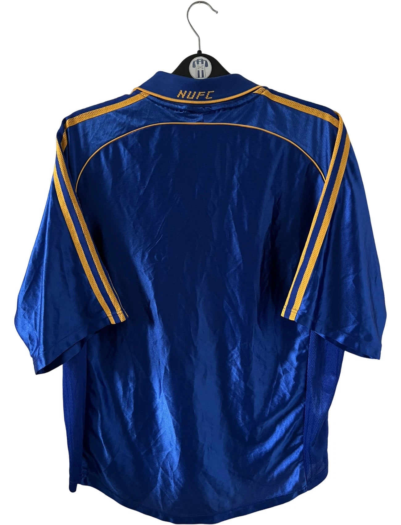 Maillot de foot vintage extérieur bleu de Newcastle 1998/1999. On peut retrouver l'équipementier Adidas et le sponsor Newcastle Brown Ale. Il s'agit d'un maillot authentique d'époque.
