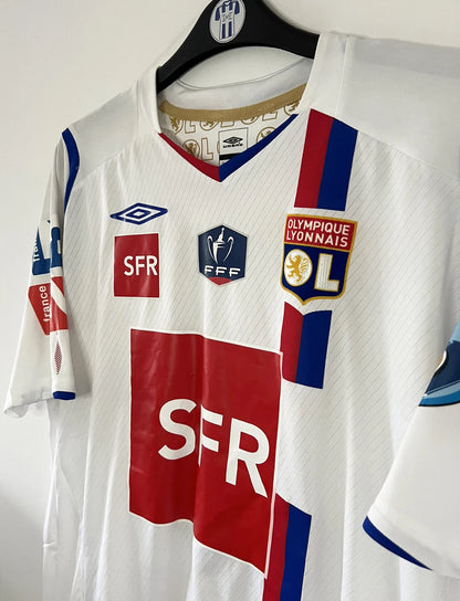 Maillot de foot vintage domicile blanc de l'OL de la saison 2007-2008. Il s'agit de l'édition coupe de france. On peut retrouver l'équipementier Umbro, ainsi que les sponsors SFR et Pitch. Le maillot est floqué du numéro 5 Mathieu Bodmer. Il s'agit d'un maillot authentique d'époque.